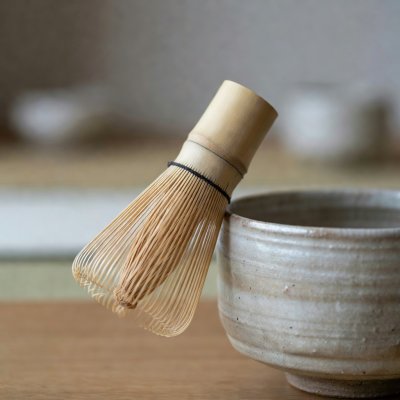 Μπαμπού σύρμα για τσάι δίπλα σε τραχύ κεραμικό μπολ, με μικρό βάθος πεδίου
